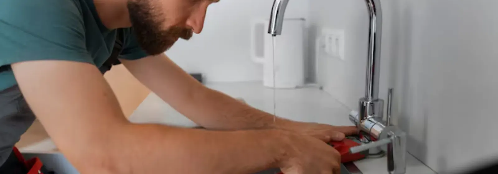 Plumber tightening a kitchen faucet with a wrench